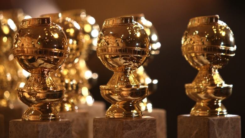 Three gold awards shaped like globes with a film reel winding around them.