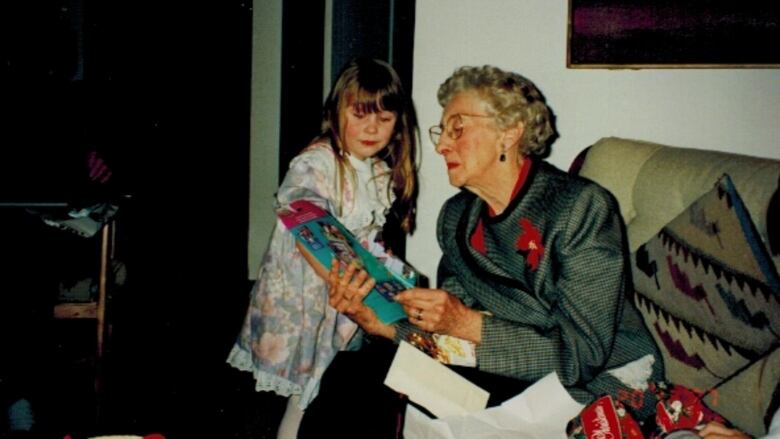 An elderly woman reads to a young girl.