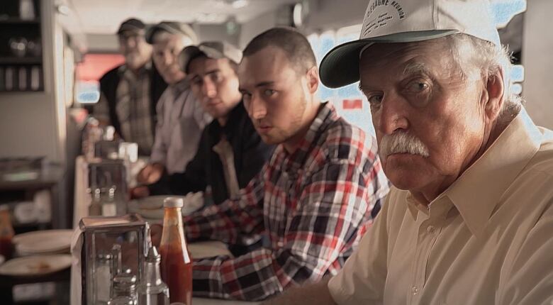 line of truck drivers sitting at counter in diner