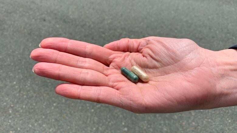 A hand holds out two pills containing psilocybin.