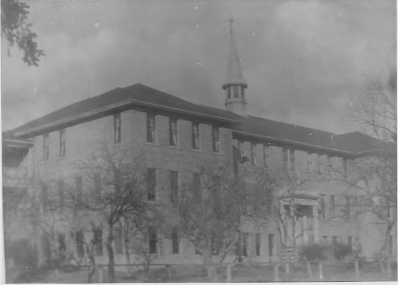 An old black and white photo of a three-story brick building. 