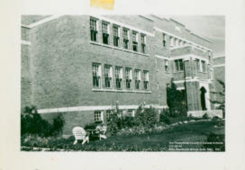 A black and white photo shows a large brick building.