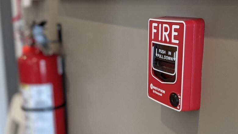 A red fire alarm sits on a wall.