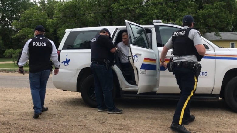 RCMP officers are seen putting a man in the back of an SUV police cruiser