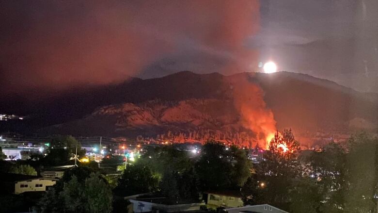 Flames engulf a building and smoke billows against a dark sky. 