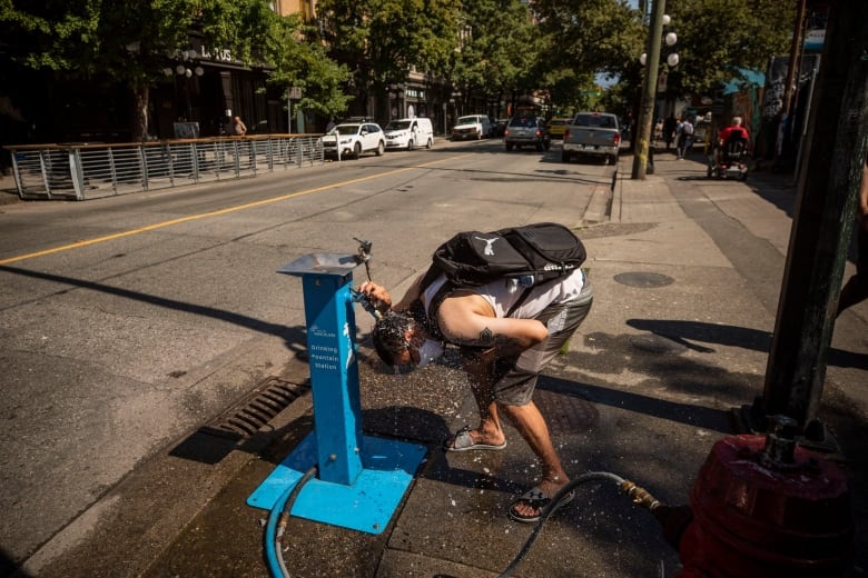 A man sprays water over his head at a public water station in Vancouver, British Columbia on Monday, June 28, 2021. 