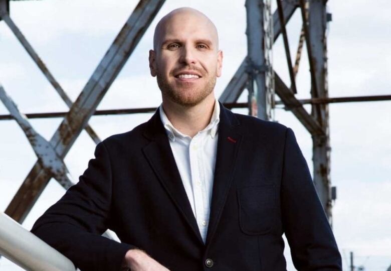 A man in a suit poses outside for a photo.