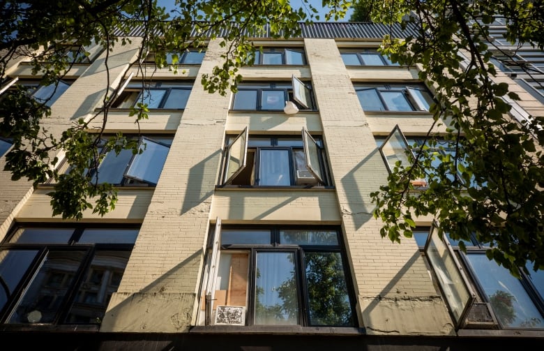 Many windows are open in a multi-storey apartment building, as seen from the perspective of someone looking up.