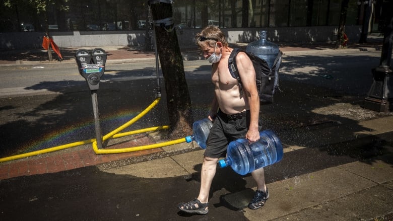 A man carries big blue water jugs