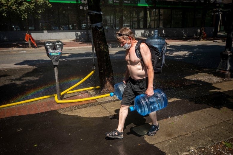 A man carries big blue water jugs