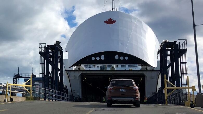 A vehicle drives onto a ramp leading to the open nose cone of the passenger ferry Confederation. 