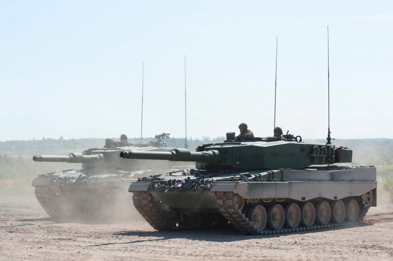 Two tanks carrying soldiers are shown side by side.