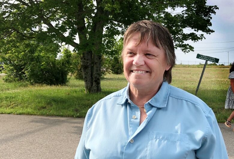 A smiling person wearing a blue shirt.