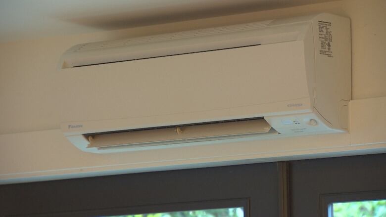 A heat pump, which is an air-conditioner-like object, hangs above a door.