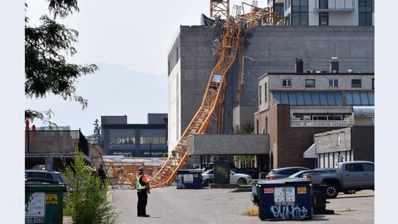 A collapsed yellow crane sits on top of a crushed office building.