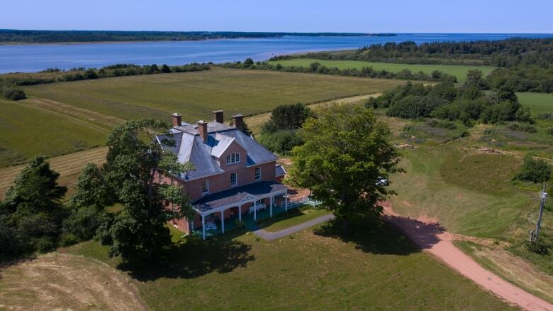 Drone footage of a three-storey brick building with four chimneys, with the sea visible in the background.