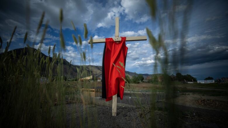 A cross with an orange tshirt on it.