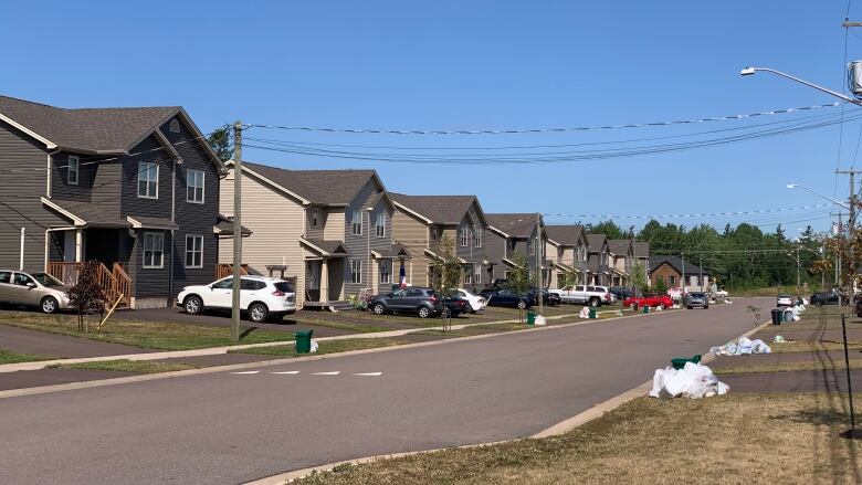 A suburban streetscape of newer homes with cars in the driveways.