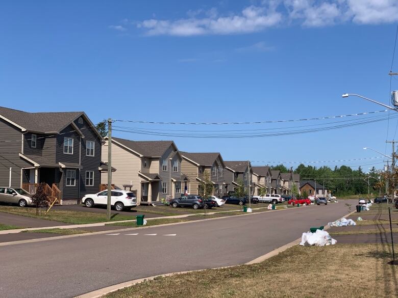 A suburban streetscape of newer homes with cars in the driveways.