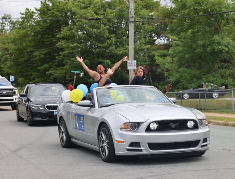 People standing in a convertible car with the roof down