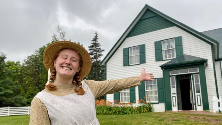 A woman dressed as Anne stands in front of Green Gables House