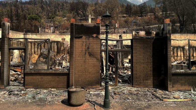 A brick structure in the foreground of burned property in Lytton B.C.