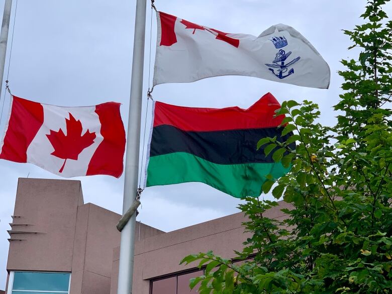 The Canadian flag, the pan African flag and the Canadian Navy Ensign are seen blowing in the wind