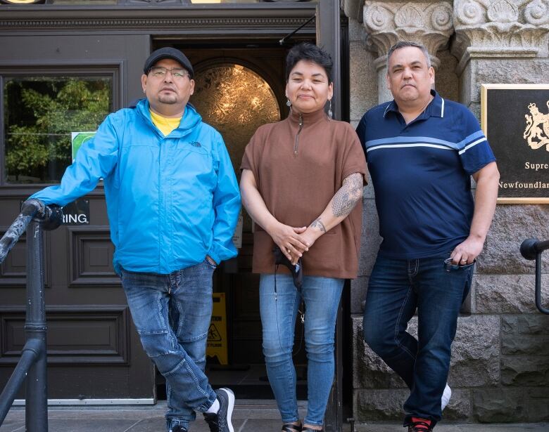 Three people standing in front of court house