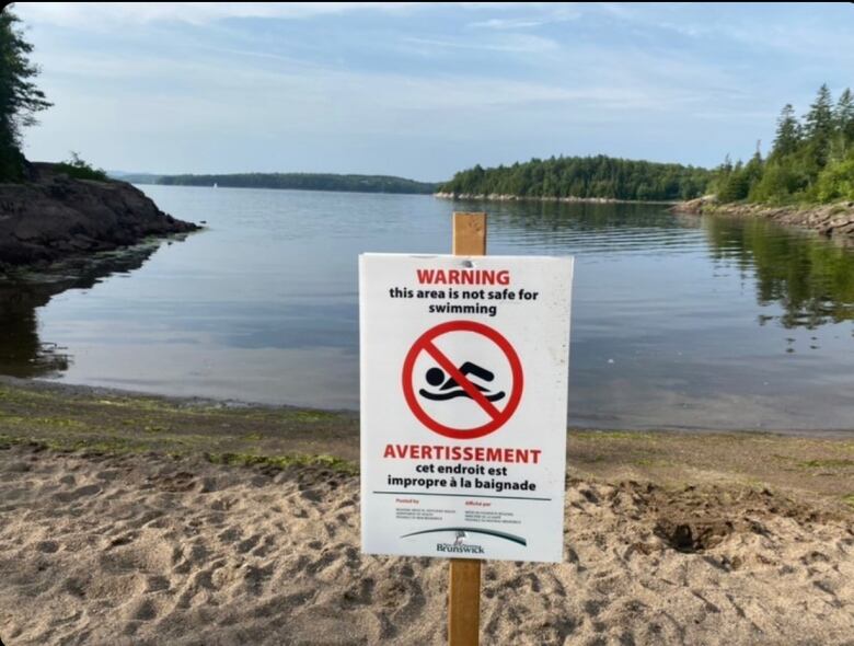 A beach in the background with a signpost in the foreground that reads 