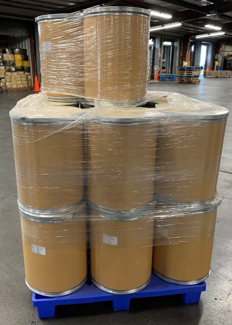 Brown barrels are stacked in a warehouse.