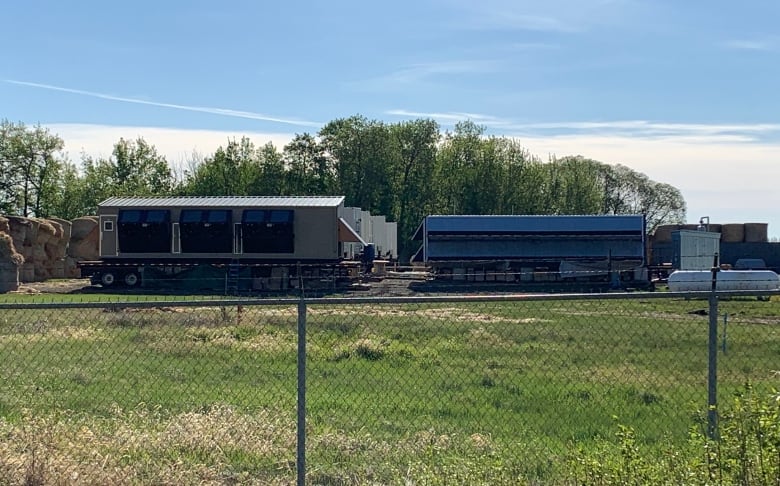 Shipping containers are seen through a fence.