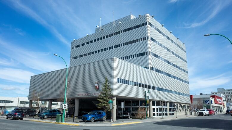 A big gray building sits on the corner. There are several floors and a shoppers drug mart in the background. 