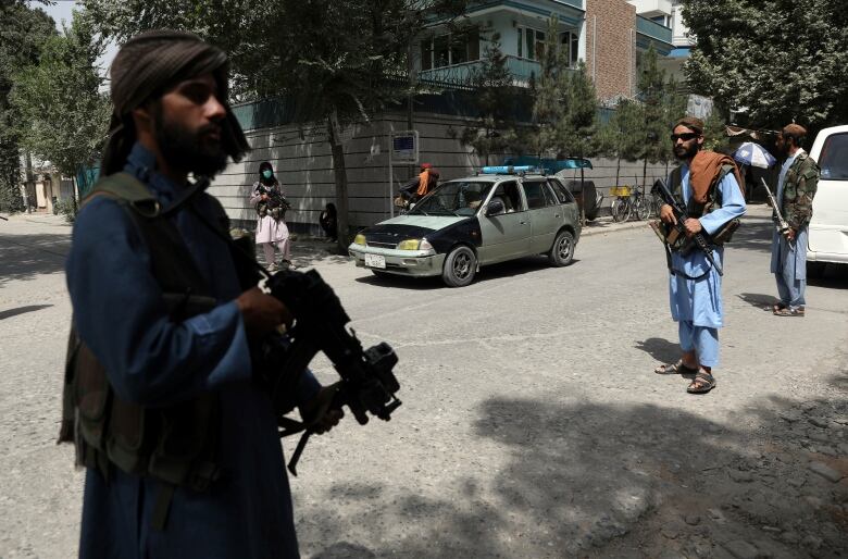 Men stand on a street with machine guns