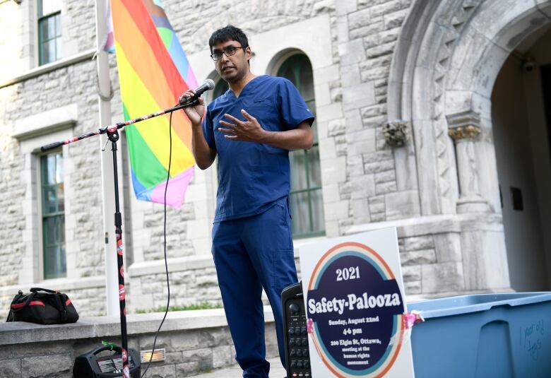 A doctor in scrubs talks into a microphone at a rally.