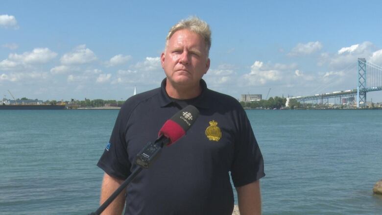 A man with the Ambassador Bridge and Detroit River in the background.