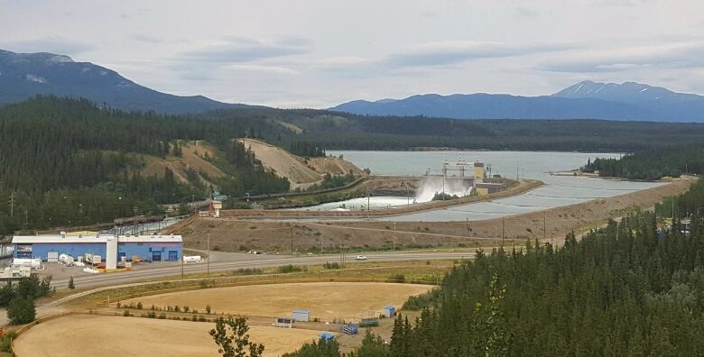 A distant view of a hydroelectirc dam with a lake and mountains in the background.