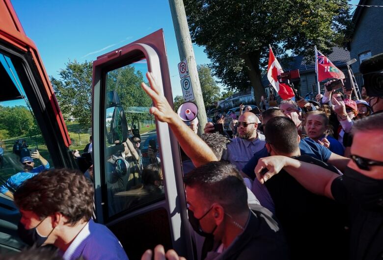 Mounties surround Justin Trudeau as he boards a campaign bus.