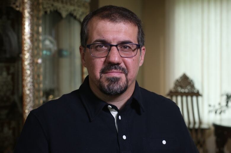 A portrait of a man with a beard wearing glasses.