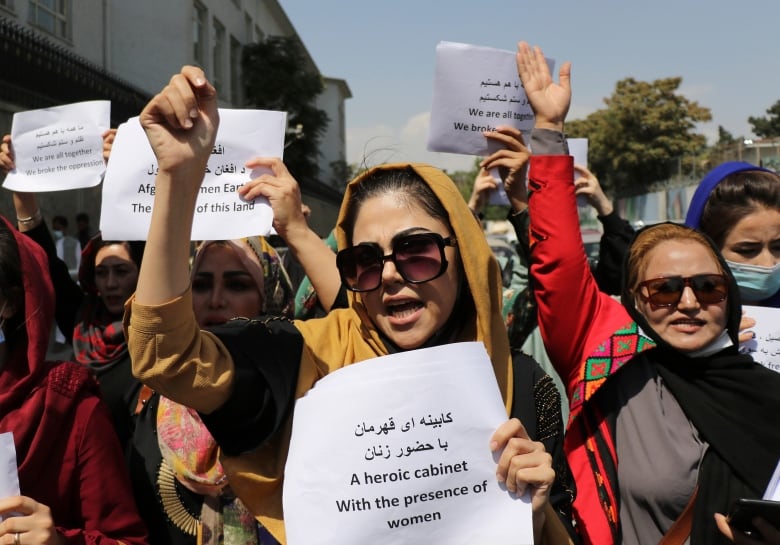 A crowd of women hold signs as they protest.