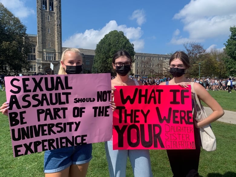 Students at a protest hold signs and wear masks. 