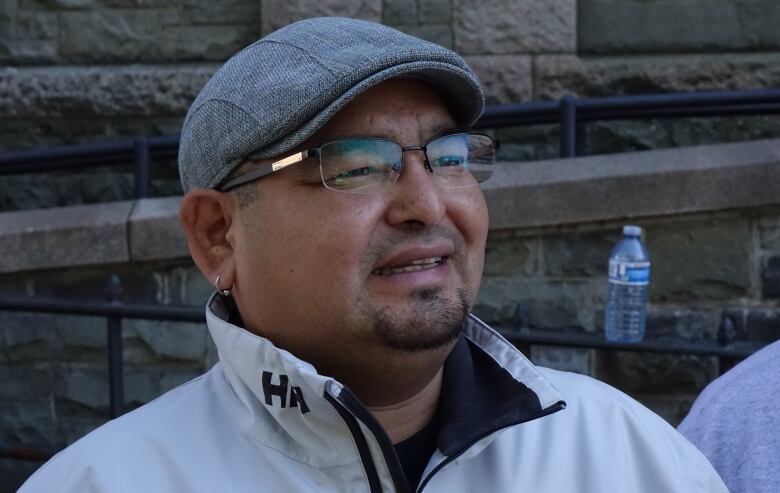 A man wearing eye glasses and a white jacket is smiling.