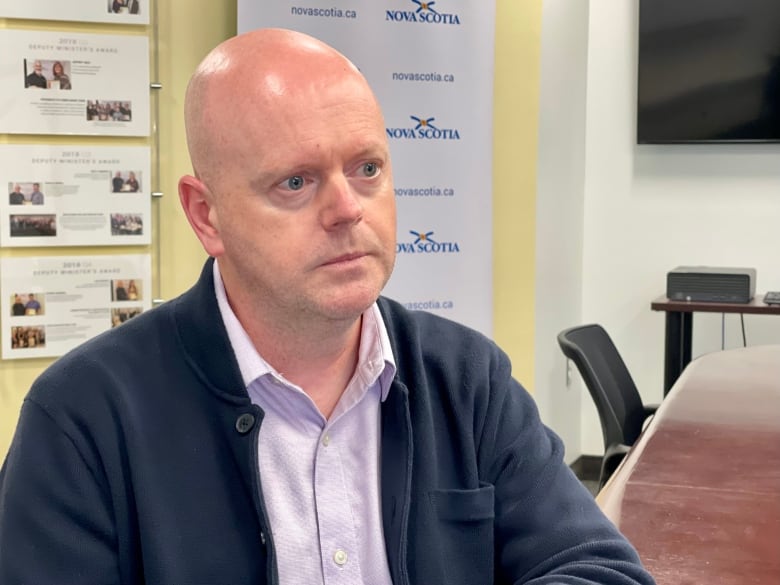 A man in blue shirt and sweater looks off camera.