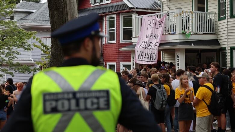 Police keep a watchful eye on a street party. A sign from a balcony reads, 'Relax, we are double vaxxed.'