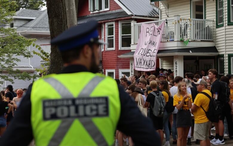 Police keep a watchful eye on a street party. A sign from a balcony reads, 'Relax, we are double vaxxed.'