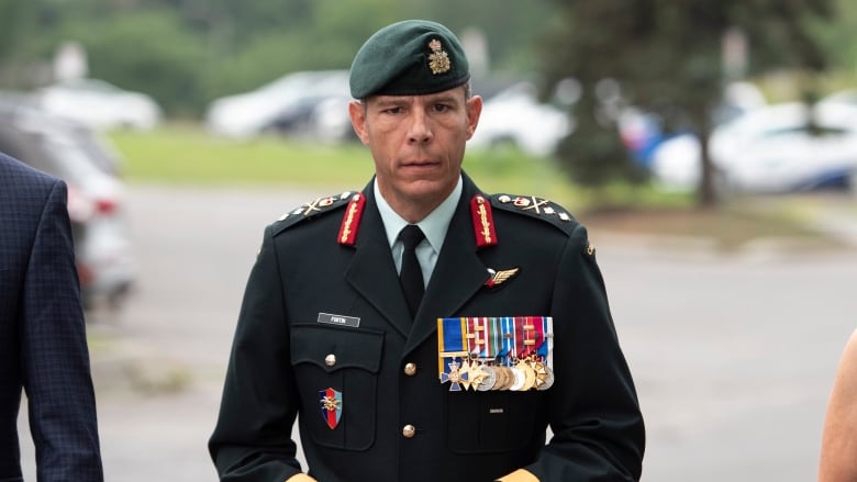 A man in a Canadian Army officer's uniform stands looking at the camera.