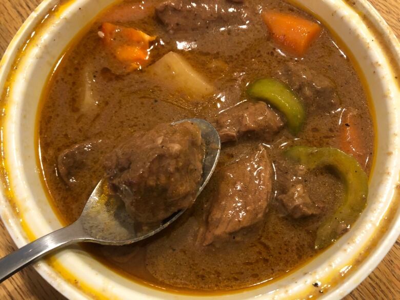 A bowl of dark brown liquid filled with chunks of meat and vegetables.