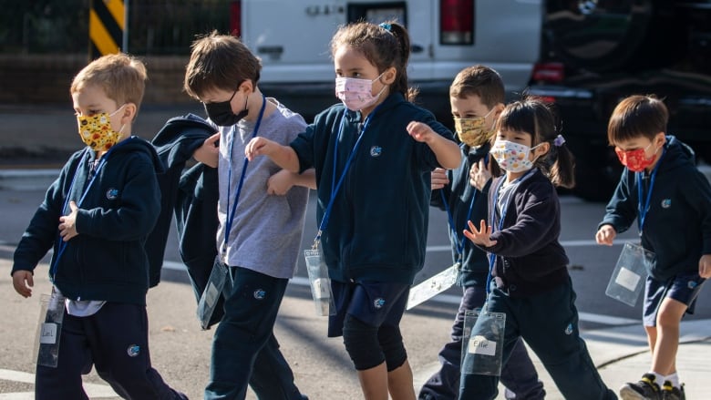 A group of masked children in a line.