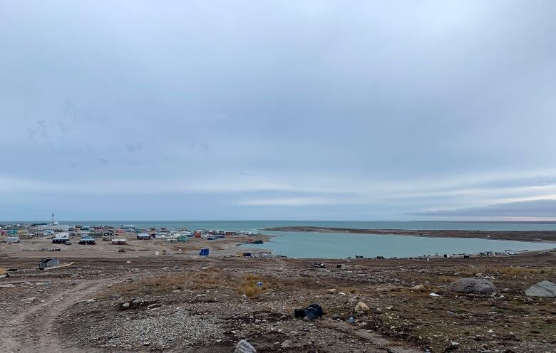 A scattering of houses and buildings on the shores of an expanse of ocean.