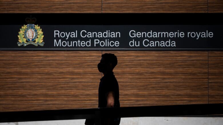 A man walks past a sign that reads 'Royal Canadian Mounted Police'.