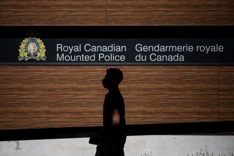 A man walks past a sign that reads 'Royal Canadian Mounted Police'.